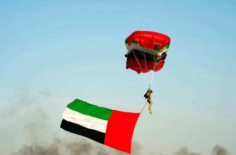 A solider parachutes down carrying the UAE flag. Wam