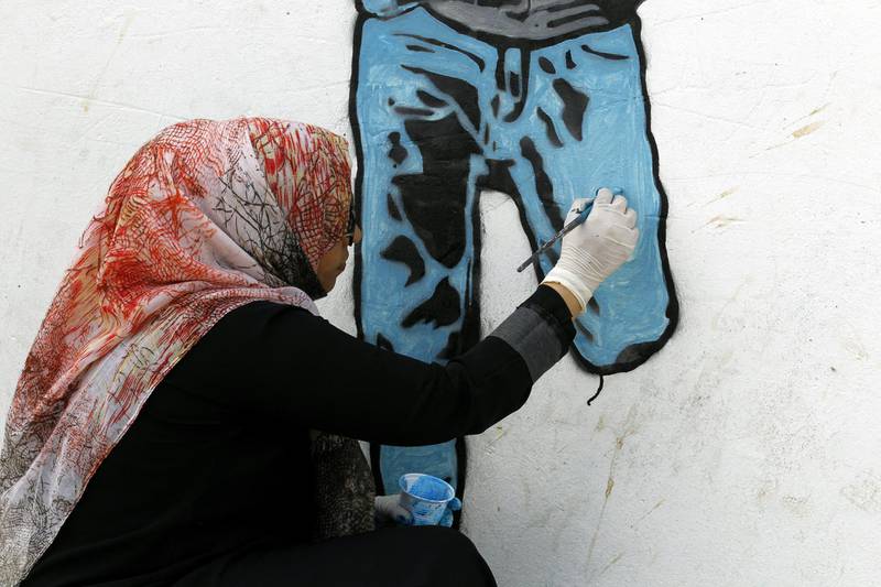 The painting of a boy with an amputated lower leg is the sixth in a series called 'Silent Victims' that Haifa Subay has painted in the rebel-held capital.  Yahya Arhab / EPA