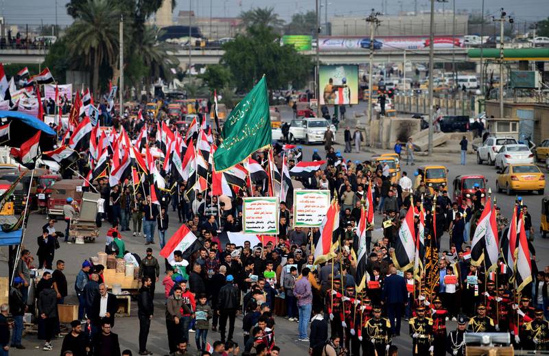 Supporters of Iraqi Shiite group Popular Crowd Forces and Iraqi Shiite Muslim spiritual leader Grands Ali al-Sistani carry the Iraqi national flag as they take part in a demonstration at the Al Tahrir square in central Baghdad.  EPA