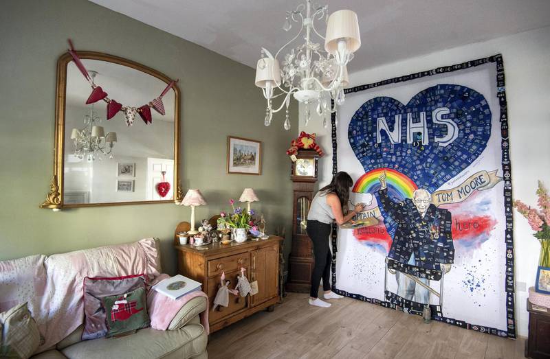 Artist Sam Bailey puts the finishing touches to a mural acknowledging the work being done by the NHS, emergency services and the fundraising exploits of Captain Tom Moore, at her home in Northampton as the UK continues in lockdown to help curb the spread of the coronavirus. (Photo by Joe Giddens/PA Images via Getty Images)