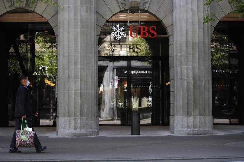 A pedestrian wearing a protective face mask walks past the entrance to the UBS Group AG headquarters in Zurich, Switzerland, on Friday, April 17, 2020. A UBS appeal of a record 4.5 billion-euro ($4.9 billion) French fine for helping clients stash undeclared funds in offshore accounts was postponed over concerns related to coronavirus pandemic, according to people familiar with the case. Photographer: Stefan Wermuth/Bloomberg