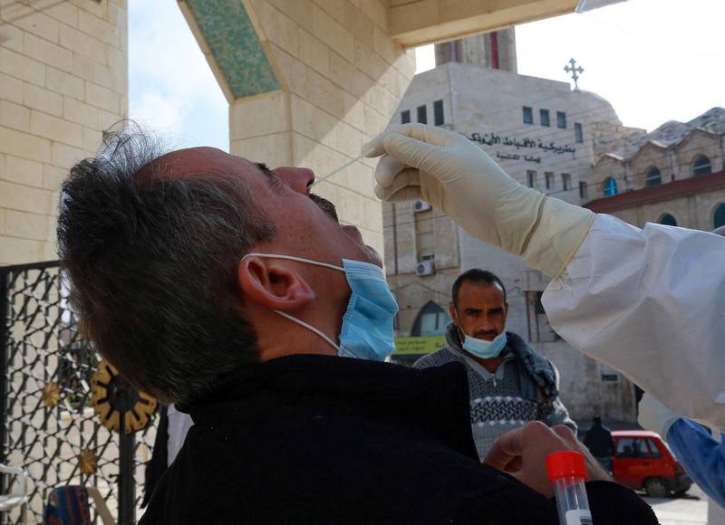 A member of the Jordanian health ministry's epidemiological investigation team, takes a random nasal swab to test for COVID-19, from a man leaving the King Abdullah I mosque following the Friday noon prayers, in the capital Amman, on December 18, 2020. (Photo by Khalil MAZRAAWI / AFP)