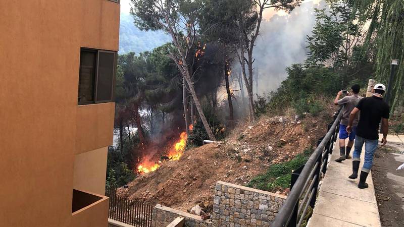 Men take photos of the fire near a residential building. Image Lebanon Civil Defence via Twitter
