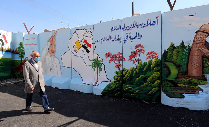 A man walks past a mural depicting the visit of Pope Francis on the concrete walls surrounding the Our Lady of Salvation Church in Baghdad. EPA