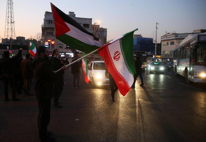 People hold Palestinian and Iranian flags as they celebrate in the street after Iran launched missiles at US-led forces in Iraq, in Tehran.  Reuters