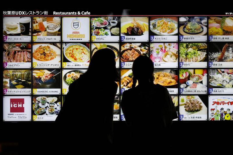 Women look at restaurant advertisement boards in central Tokyo. A planned sales tax rise has been put on hold by the government, concerned at persistently low consumer spending. Toru Hanai/Reuters