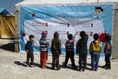 Displaced Syrian children read a poster, outlining seven steps to prevent the spread of Covid-19, at a camp for the internally displaced near Dayr Ballut, near the Turkish border in the rebel-held part of Aleppo province.  AFP