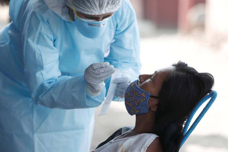 A healthcare worker wearing personal protective equipment (PPE) takes a swab sample from a woman for the coronavirus disease (COVID-19) in Cantagallo, an indigenous Shipibo-Conibo community, during the vaccination campaign against the coronavirus, in Lima, Peru February 19, 2021. REUTERS/Angela Ponce