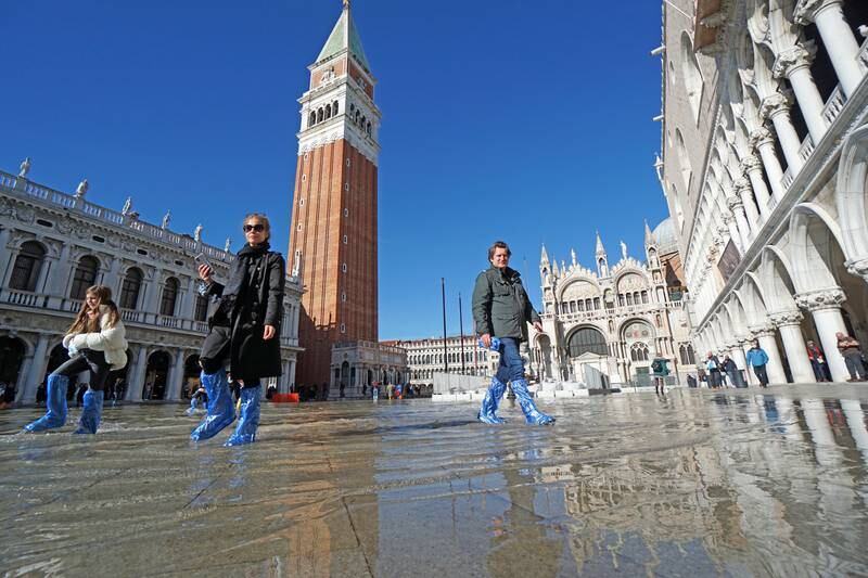 Tourists wearing galoshes walk in the flooded San Marco Square, in Venice last week. At a tidal peak of 101 centimetres, the Mose protection system was not activated, but the area was still under water. EPA