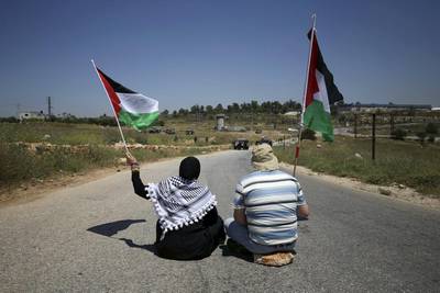Palestinian protesters wave flags as Israeli troops take position during a protest against Jewish settlements in the West Bank village of Nabi Saleh, near Ramallah.  Reuters