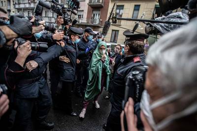 Silvia Romano, escorted by Carabinieri, arrives at her home wearing a surgical mask to guard against Covid-19, in Milan, Italy.  AP Photo