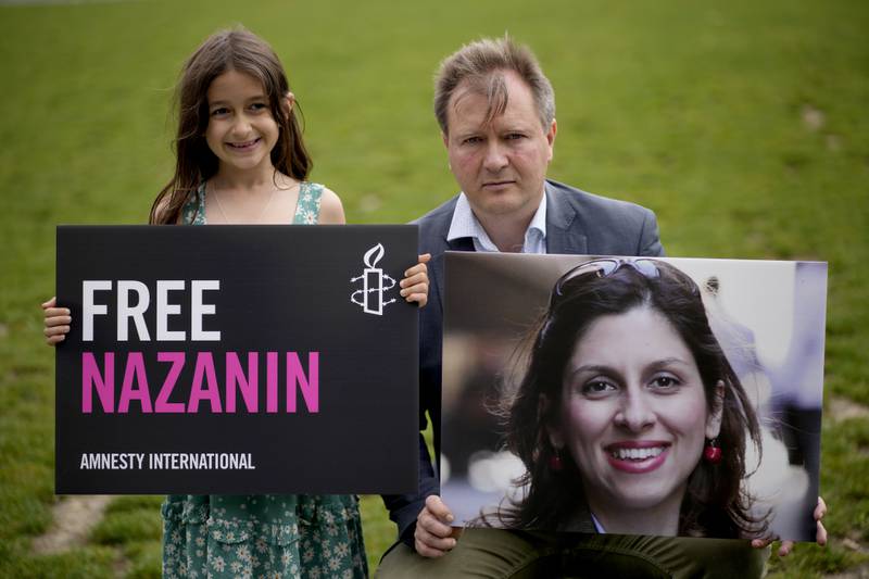 Richard Ratcliffe, the husband of imprisoned Nazanin Zaghari-Ratcliffe, and their 7-year-old daughter Gabriella hold up pictures of Nazanin in Parliament Square in London in September 2021, to mark the 2,000 days she has been detained in Iran. AP
