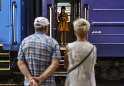 A young girl with her dog waves goodbye to her grandparents from an evacuation train leaving Pokrovsk in August 2022