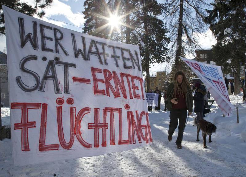 A protest banner reads ‘Arms produce refugees’, at the World Economic Forum in Davos, Switzerland, last year. The annual meeting brings together chief executives, heads of state and economists to discuss issues such as the climate, technology and conflict. Michel Euler / AP Photo.