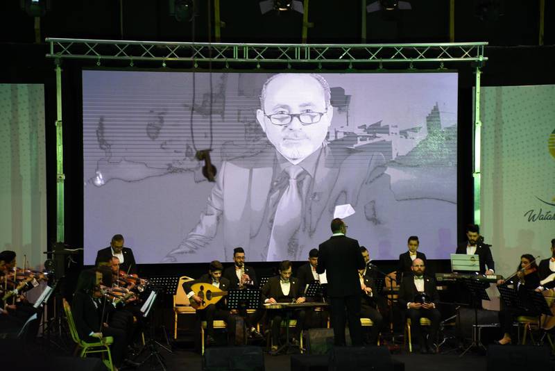 Images of famous Iraqi cultural and art personalities are shown on a screen during the concert by the Watar orchestra. EPA