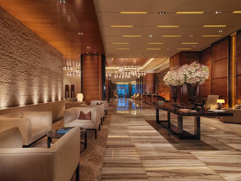 The elegant lobby features mostly dark wood paired with muted tones. Photo: Rosewood Hotels