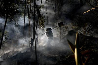 A fireman walks through the smoke of a mountain fire in Soacha near Bogota. AP