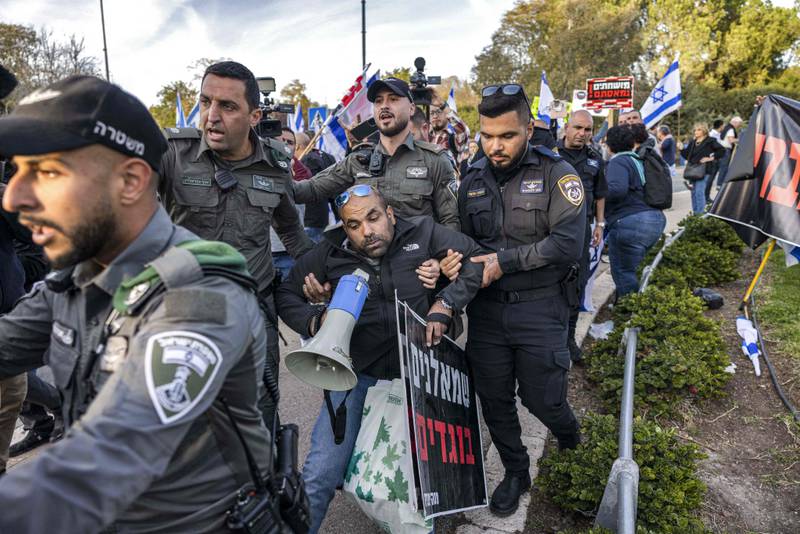 Israeli security forces remove a right-wing activist holding a megaphone and a sign reading in Hebrew "leftists are traitors" during a protest by left-wing activists against the government coalition proposed by prime minister-designate Benjamin Netanyahu near the Knesset on Monday. AFP