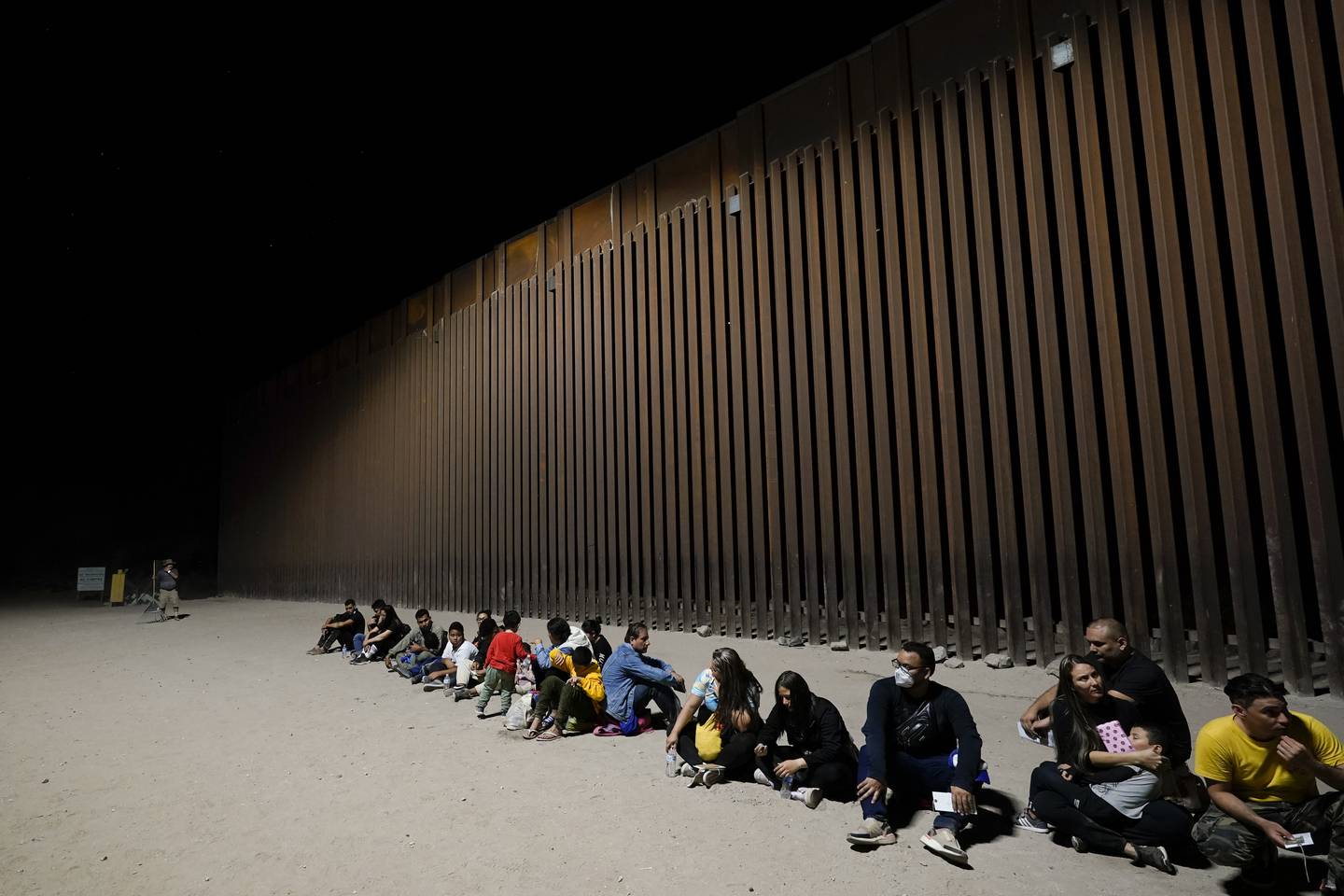 Migrants wait near the end of a border wall near Yuma, Arizona. AP
