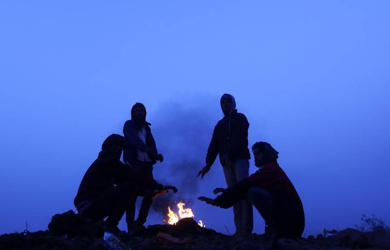 Indian labourers warm themselves around a bonfire  on the outskirts of Jammu.  AFP