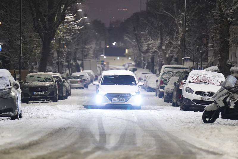 A car negotiates a snow-covered road in Willesden Green, north-west London. PA