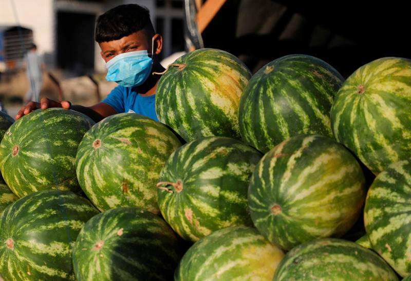 A mask-clad child sells watermelons in the Askar Palestinian refugee camp, east of the West Bank city of Nablus. AFP
