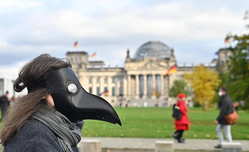 A protester wearing a mask walks past the Reichstag building housing the Bundestag in Berlin. AFP