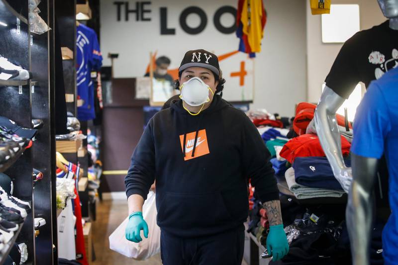 A worker wears protective equipment after assisting a customer select her purchases from curb-side at The Loop fashion and shoe store as businesses slowly begin to reopen in Yonkers city, New York. AP