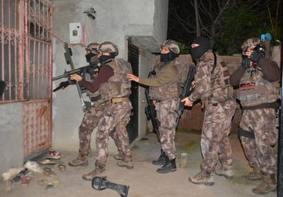 Turkey's special police officers prepare to storm a house during an operation to arrest Islamic State group suspects, in the southern city of Adana, Turkey, early Wednesday, March 7, 2018. Turkey's state-run news agency says police in simultaneous dawn raids at homes, have detained 13 Islamic State group suspects who were allegedly plotting attacks on a number of buildings in the city, including the U.S. Consulate. (Gokhan Keskinci/DHA-Depo Photos via AP)