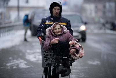 An elderly woman is carried in a shopping cart after being rescued from Irpin, on the outskirts of Kyiv, Ukraine. AP