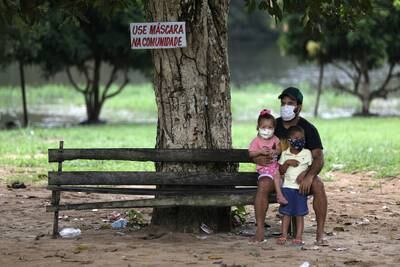 A man with his children are seen next to a sign that reads, "Use mask at the community" at Nossa Senhora do Livramento community in Manaus, Brazil.