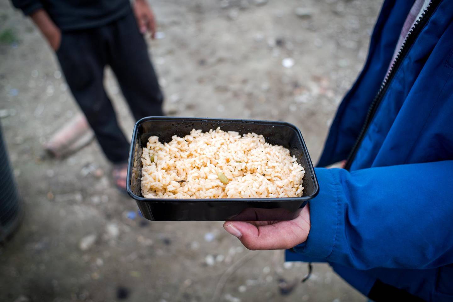 A Syrian refugee is showing me the food that has been served to the camp, and describing it as bad.