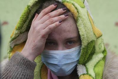 A woman waits outside the damaged hospital in Mariupol. AP