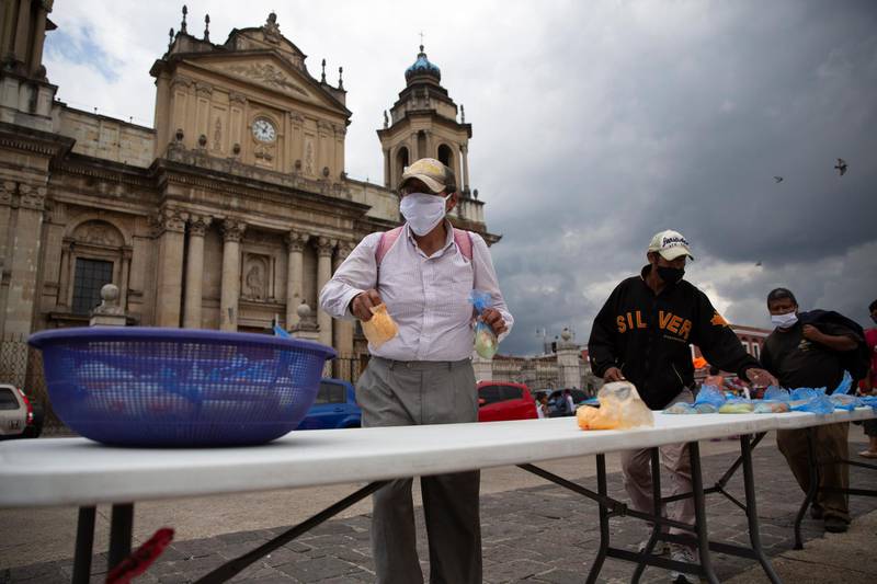 Unemployed people affected by the restrictions put in place to prevent the spread of the new coronavirus take food donated by a Catholic family in front of the Metropolitan Cathedral in Guatemala City, Guatemala. AP Photo