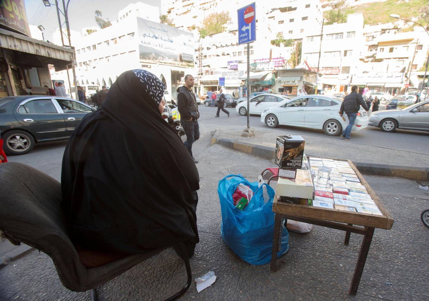 Iraqi refugee Um Saad sits on the sidewalk of a street selling sigarettes for living in the downtown in Amman, Jordan. (Salah Malkawi for The National)