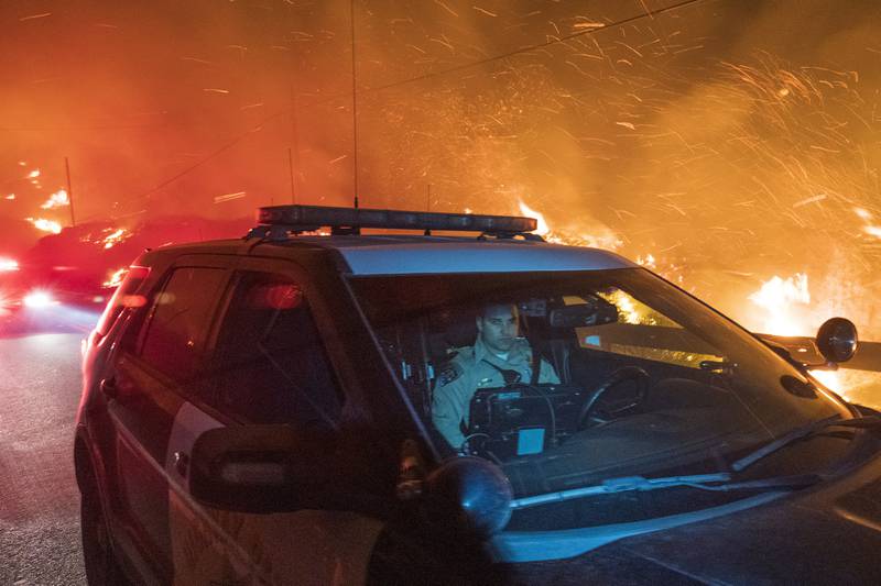 A California Highway Patrol officer drives south on Highway 1 as the Colorado Fire burns near Big Sur. Strong winds were forecast for Friday into Saturday at high elevations.