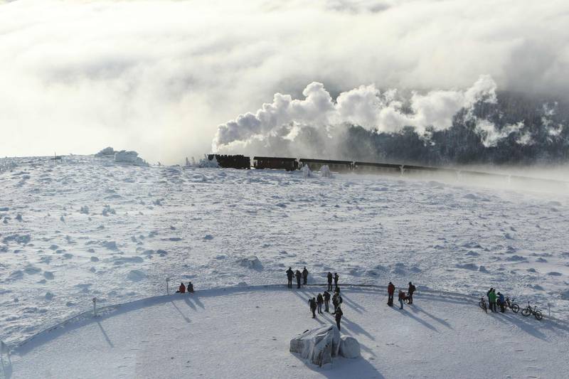 Tourists look on as the Harzer Schmalspurbahn narrow gauge train makes its way through the snowy landscape on the Brocken mountain near Schierke, central Germany. AFP