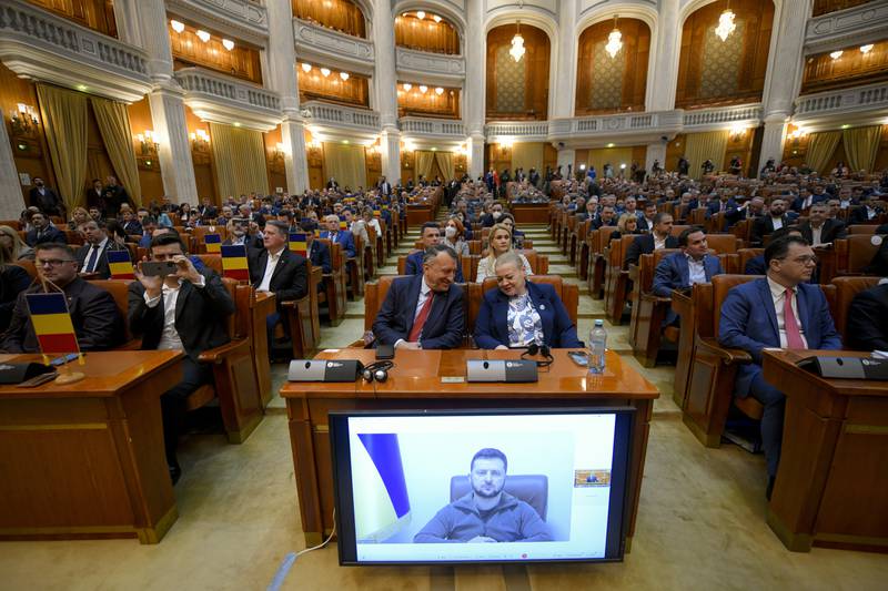 Romanian politicians listen to President Zelenskyy’s speech by video link, on a screen in the parliament in Bucharest. AP