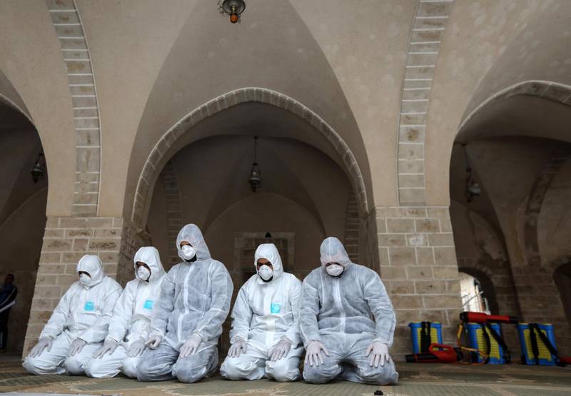 Palestinian workers wearing protective gear, pray in the courtyard of the al-Omari mosque, after spraying disinfectant products as a means of prevention against the spread of the coronavirus COVID-19, in Gaza City. AFP