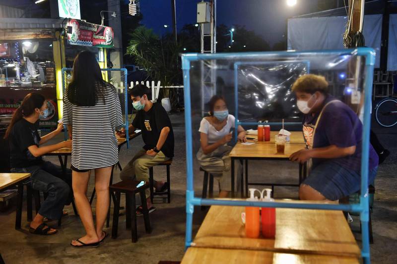 People eat at tables with plastic dividers, as a preventive measure at the Srinagarindra Train Night Market in Bangkok, Thailand. AFP