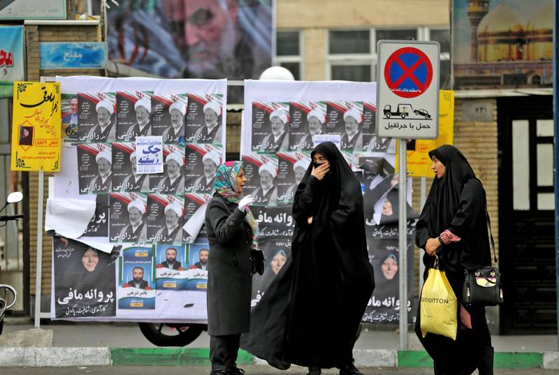 Iranian women chat in front of electoral posters. AFP