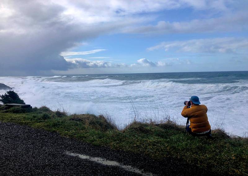 A man photographs waves crashing onto the cliffs at Rodea Point in Lincoln County, Oregopn during an extreme high tide that coincided with a big winter storm. AP Photo/Gillian Flaccus