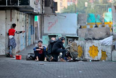 Protesters take cover during clashes with security forces in Baghdad, Iraq. AP Photo