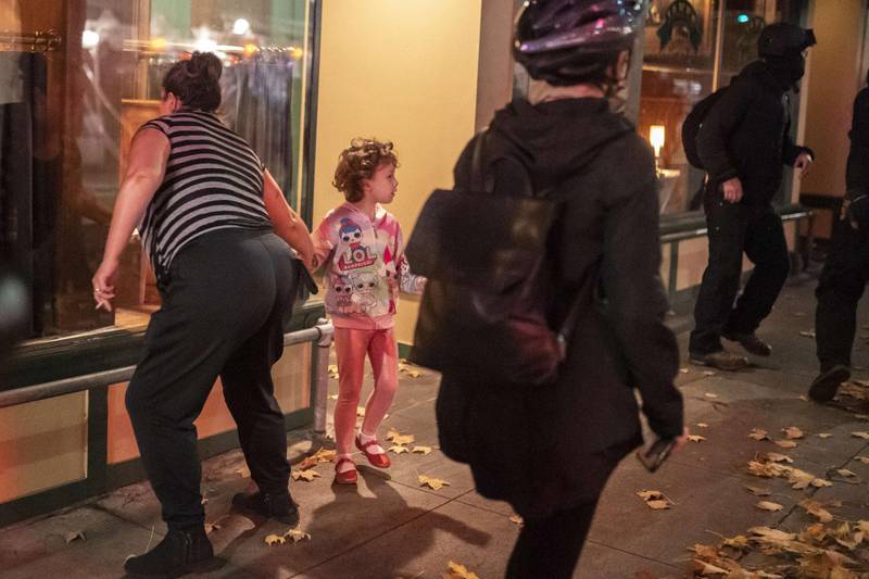 A woman pulls a child away from a protest crowd as it passes a downtown restaurant in Portland, Oregon. AFP