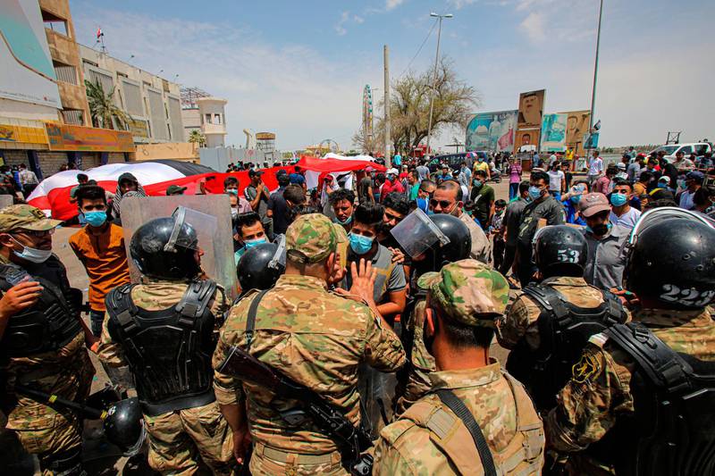 Riot police secure the area as protesters gather in Basra, Iraq.  AP