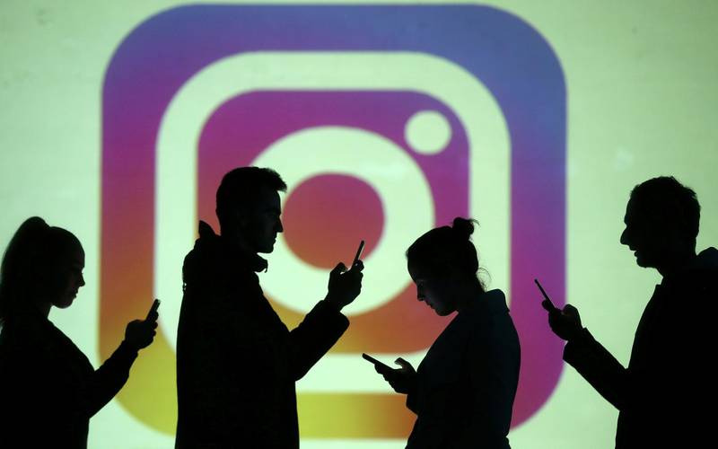 FILE PHOTO: Silhouettes of mobile users are seen next to a screen projection of the Instagram logo in this picture illustration taken March 28, 2018.  REUTERS/Dado Ruvic/Illustration/File Photo