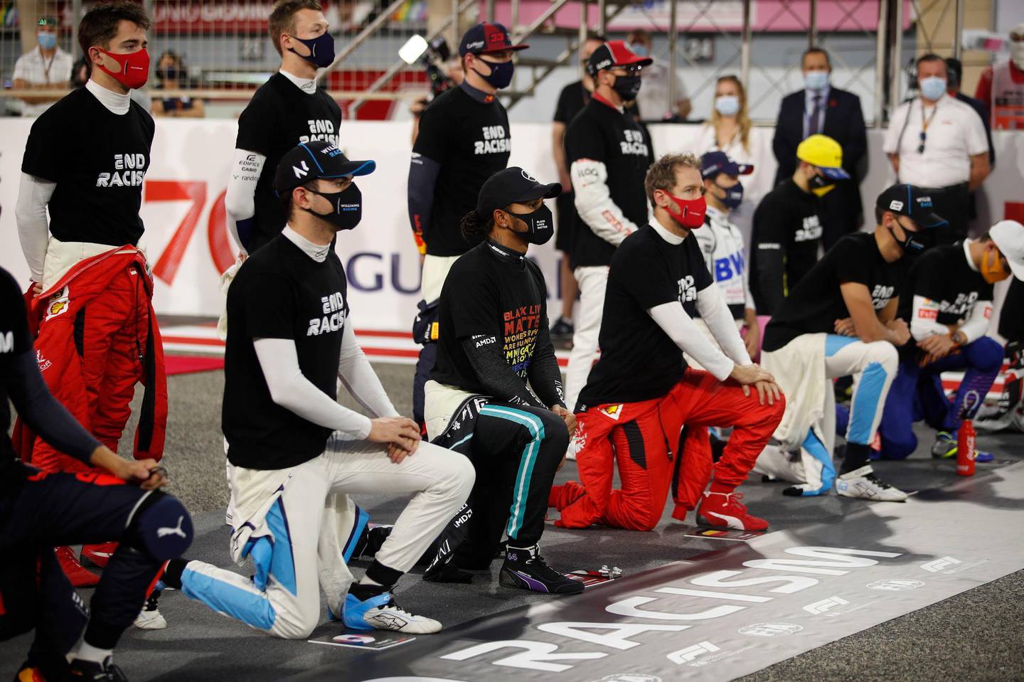 Mercedes driver Lewis Hamilton of Britain , centre, and Ferrari driver Sebastian Vettel of Germany, right, take the knee in support of the Black Lives Matter campaign and End Racism Recognition event ahead of the Bahrain Formula One Grand Prix at the Bahrain International Circuit in Sakhir, Bahrain, Sunday, Nov. 29, 2020. (Hamad Mohammed, Pool via AP)