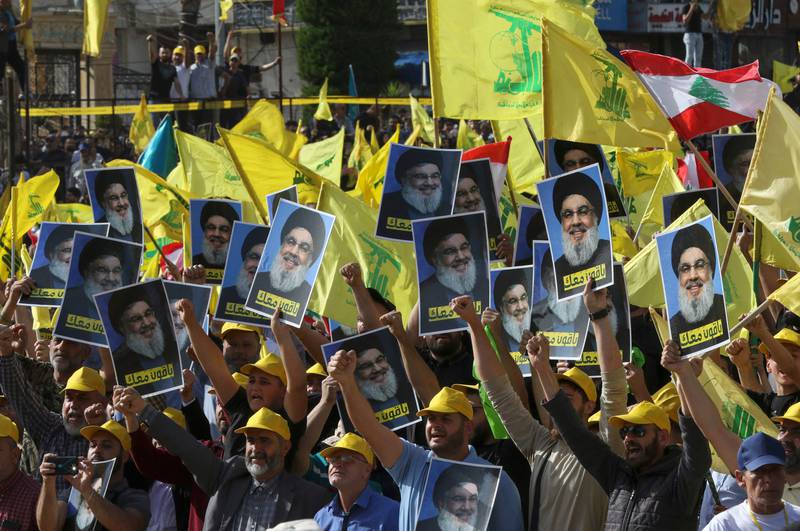 Supporters of Hezbollah lift portraits of the group's leader Hassan Nasrallah as they attend his speech, broadcast on a giant screen, in the southern city of Nabatieh on Tuesday. AFP
