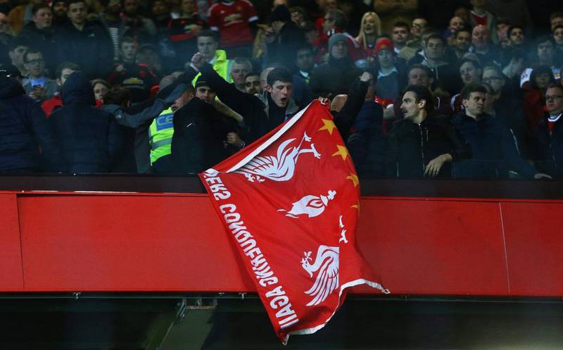 A Liverpool fan holds a flag as he stands amongst Manchester United supporters after their Europa League last-16, second-leg match at Old Trafford on Thursday. Clive Brunskill / Getty Images