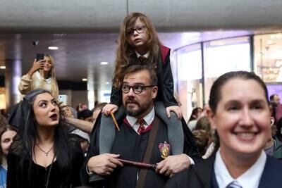 Harry Potter fans Remy Mckenzie, her daughter Elizabeth, five, and her husband Jason McKenzie, attend Back to Hogwarts Day at King's Cross Station in London. Reuters